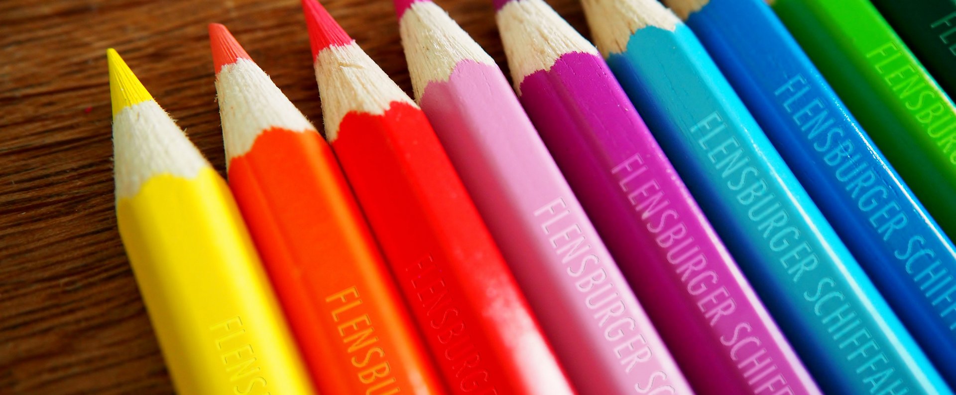 Auf einem Tisch liegen Buntstifte. Alle sind mit dem Schriftzug „Flensburger Schifffahrtsmuseum“ geprägt.