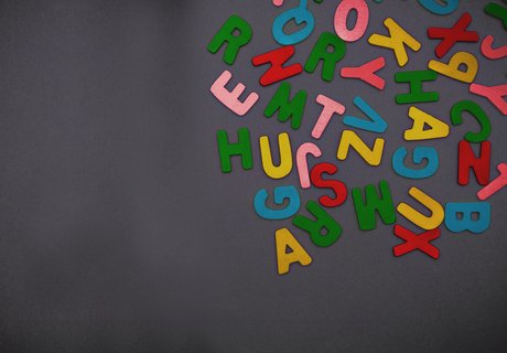 Kolorerede træbogstaver ligger på en sort baggrund.