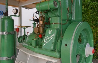 Der grüne Glühkopfmotor steht im Flensburger Schifffahrtsmuseum draußen neben der Technikhalle.