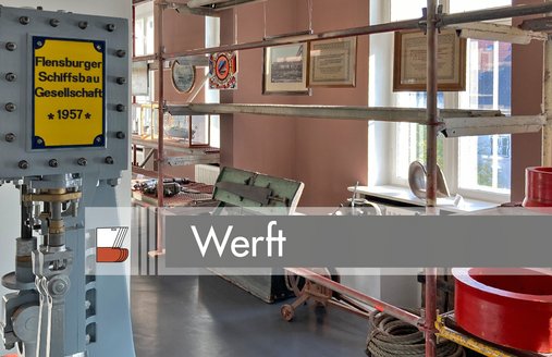 Til venstre står en maskine med et gult skilt. På skiltet står der: Flensburger Schiffsbau Gesellschaft 1957. Til venstre for maskinen står en lang metalreol. Der hænger billeder ned fra reolens hylder. Det er dokumenter og fotografier fra et skibsværft. På reolerne ligger forskellige værktøjer – f.eks. en nittehammer helt bagest på billedet.