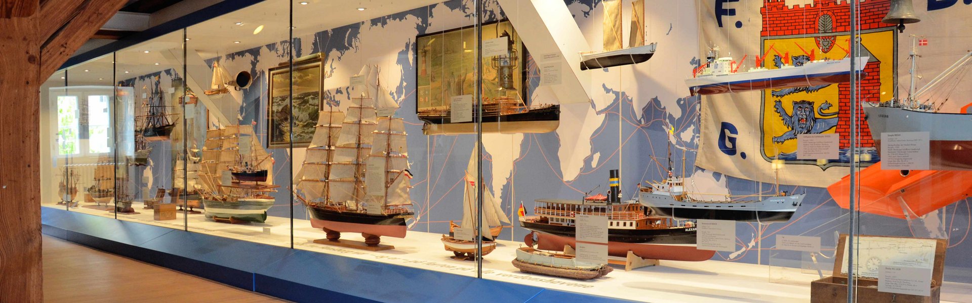 In der Ausstellung HAFEN & HÖFE gibt es eine ganz große Vitrine, die sich einmal über die gesamte Breite des Raumes zieht. In der Vitrine sind verschiedene Flensburger Schiffe zu sehen.
