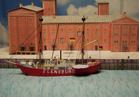 Skibet FLENSBURG ligger foran havnekontoret. Både skibet og bygningen er lavet af pap af vores papmodeller.