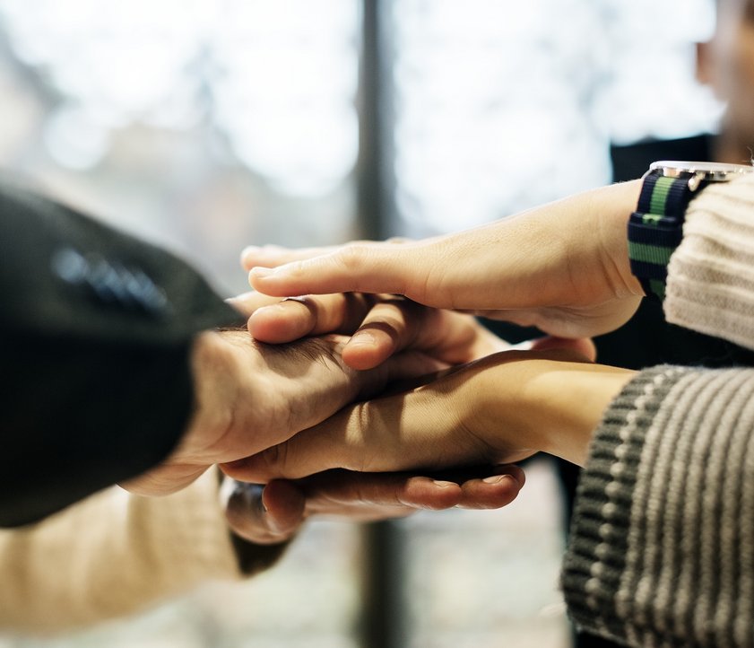 På billedet kan man se, at forskellige hænder rækkes mod midten.