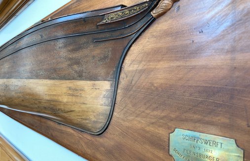  På en væg hænger et halvskib fra FSG. Det er et nærbillede.