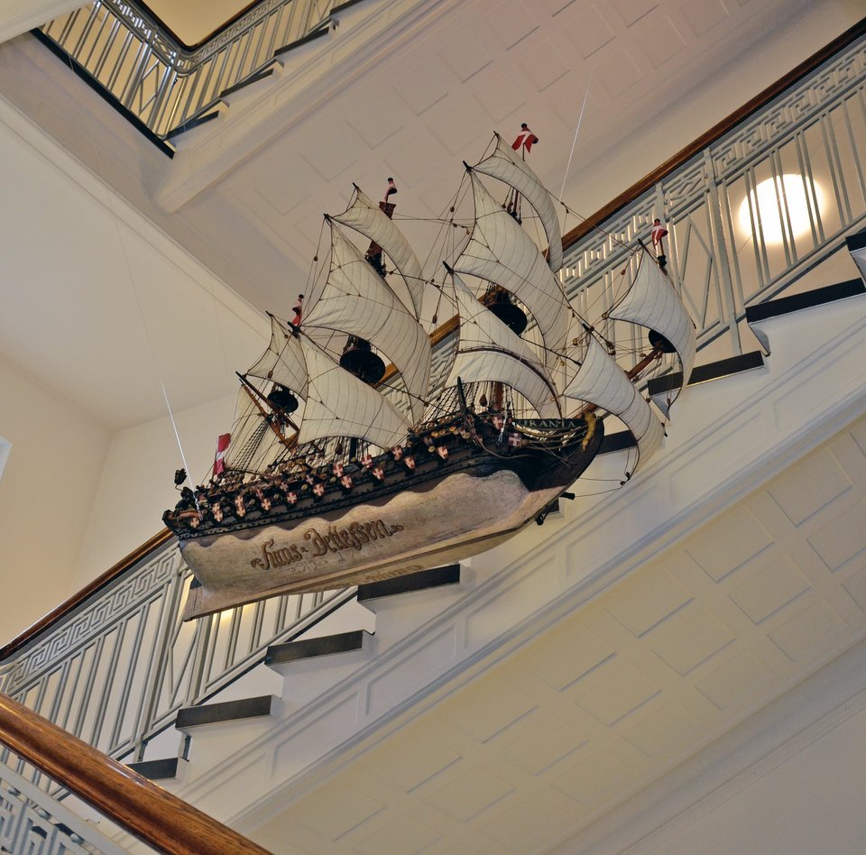 Im Treppenhaus des Hinterhauses hängt ein Votivschiff. Es ist ein Segelschiff, das auch Holz gebaut worden ist. Es ist mit vielen Kanonen ausgerüstet. Das Schiff fährt unter dänischer Flagge.