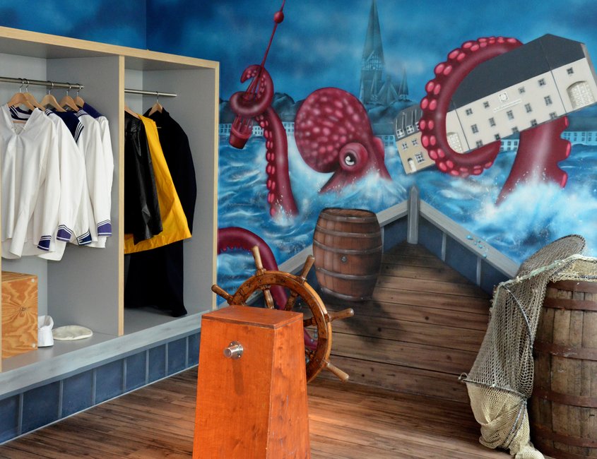 Im Flensburger Schifffahrtsmuseum kann man sich verkleiden und vor einer Wand fotografieren. Auf der Wand ist ein Bild von einem Riesenkraken gesprüht, der das Gebäude des Schifffahrtsmuseums mit seinem Tentakel festhält. Das Graffiti deutet an, dass man sich auf einem Schiff befindet und direkt auf den Riesenkraken zusteuert.