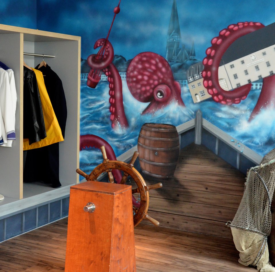 Im Flensburger Schifffahrtsmuseum kann man sich verkleiden und vor einer Wand fotografieren. Auf der Wand ist ein Bild von einem Riesenkraken gesprüht, der das Gebäude des Schifffahrtsmuseums mit seinem Tentakel festhält. Das Graffiti deutet an, dass man sich auf einem Schiff befindet und direkt auf den Riesenkraken zusteuert.