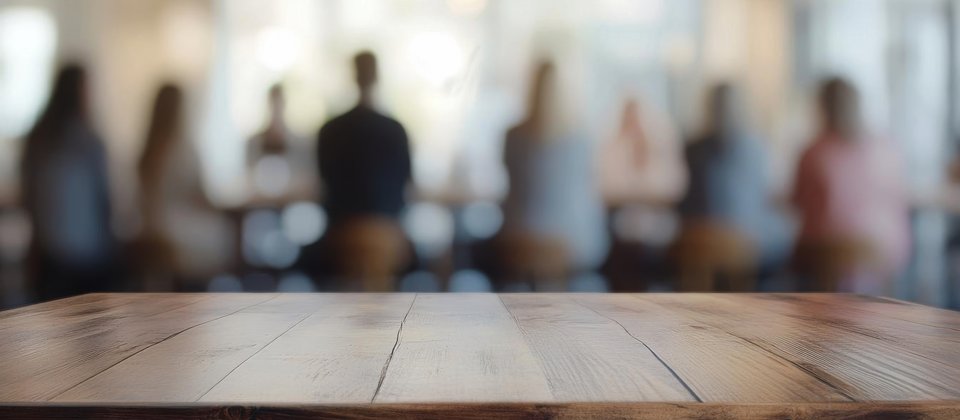 Billede af en flok mennesker, der sidder rundt om et bord. Man kan bare se dem bagfra.