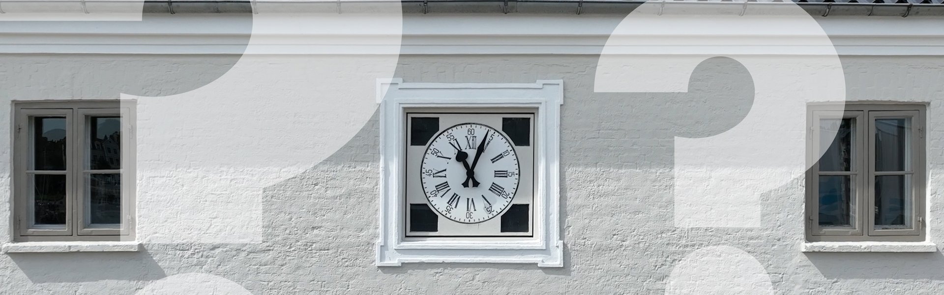 Auf dem Foto ist die Fassade des Schifffahrtsmuseums zu sehen. Sie ist geklinkert und hell angestrichen. Die Sprossenfenster sind dunkel abgesetzt. In der Mitte der Fenster ist direkt unter dem schwarzen Dach eine Uhr in die Mauer eingelassen. Laut ihr ist es kurz nach 11 Uhr. Unter der Uhr ist ein Schild angebracht, das die Aufschrift „Schiffahrtsmuseum“ trägt. Über dem Foto sind verblaste Fragenzeichen gelegt.