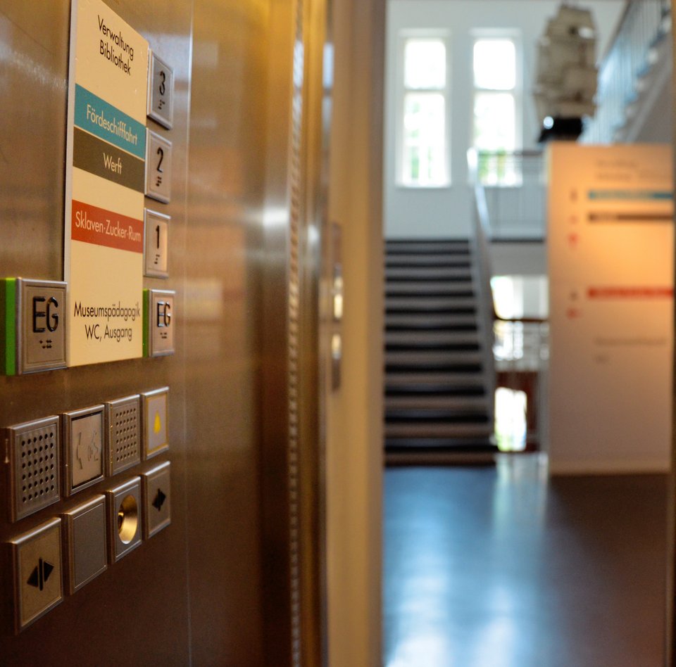 Biledet er taget fra elevatoren, der befinder sig i den bageste bygning, og viser trappeopgangen. Der hænger en votivskib fra loftet.